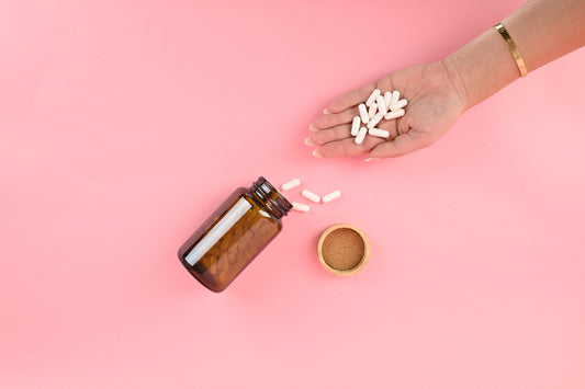 Hand holding white pills spilling from bottle